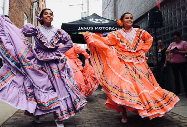 Two women dressed in cultural attire dancing in the street